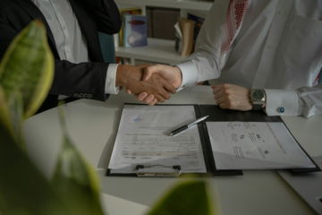 two-people-shaking-hands-over-a-piece-of-paper.jpg two people shaking hands over a piece of paper