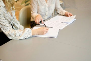 woman-signing-on-white-printer-paper-beside-woman-about-to-touch-the-documents.jpg woman signing on white printer paper beside woman about to touch the documents